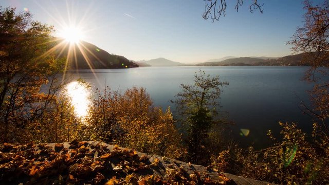 Time lapse - Sunset at the lake at autumn with leaves in the foreground