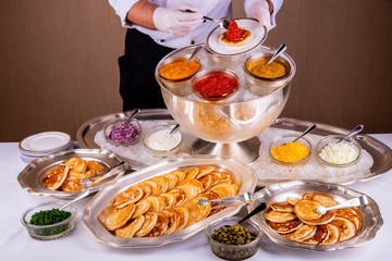 The chef does pancake with red caviar on a plate