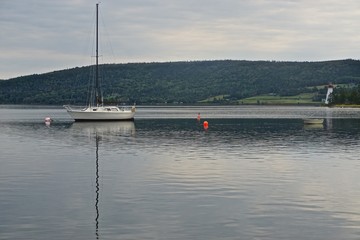 Baddeck, Nova Scotia, Canada: Sailboat anchored in Bras d&rsquo;Or Lake on Cape Breton Island, with the Kidston Island Lighthouse (1912) on the far right.