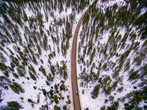 Aerial of a car driving on a road with nearby trees