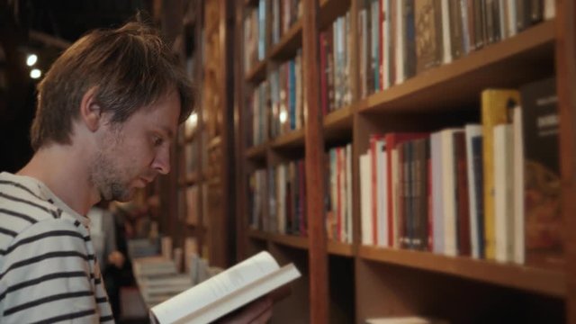 Handsome bearded student tourist man reading book in library store shop supermarket choose dictionary