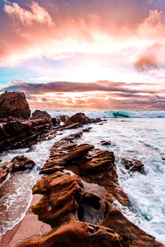Waves crashing against rocks at sunset