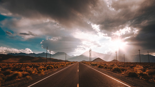 Sun peering through clouds over a highway