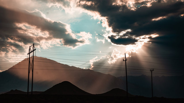 Telephone poles with mountains in the background and billowing clouds