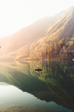 People in a boat in the middle of a lake surrounded by mountains