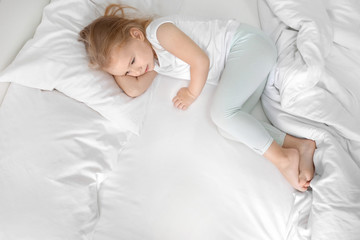 Little girl lying on white pillow at home