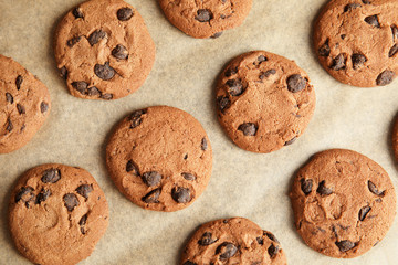 Tasty chocolate chip cookies on parchment, flat lay