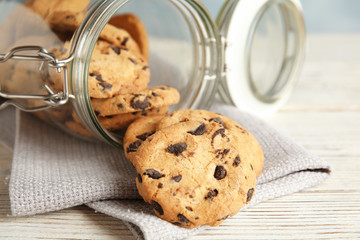 Jar of tasty chocolate chip cookies on wooden background