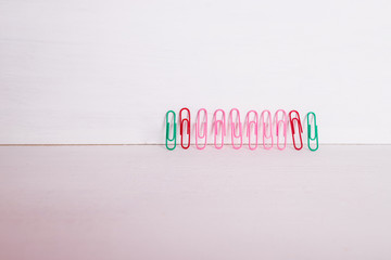 Fototapeta premium office supplies.The composition row of multi-colored paper clips on pnk, pastel background.Colorful paper clips isolated.Copy space.Creative composition.Minimalism concept.Arts and crafts material