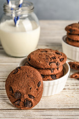 Bowl with tasty chocolate chip cookies on wooden table