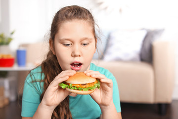 Overweight girl eating burger indoors