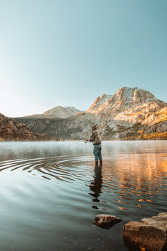 Person fishing with mountains in the distance