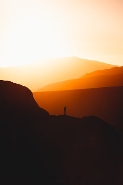 Silhouette of person standing on mountain during sunset