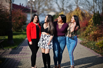 Group of four happy and pretty latino girls from Ecuador posed at street.