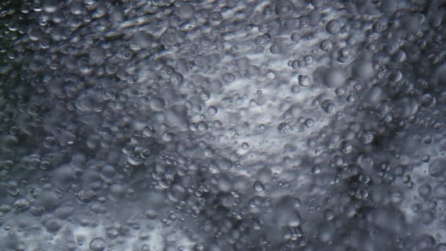 Sparkling water running in front of bright background in slowmotion