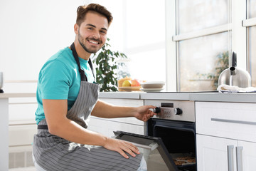 Young man baking cookies in oven at home