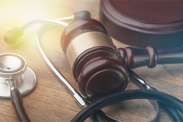 Gavel and stethoscope on wooden background, symbol photo for