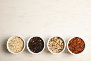 Flat lay composition with different types of quinoa and space for text on white wooden background