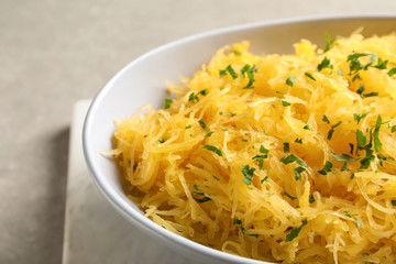 Bowl with cooked spaghetti squash on light background, closeup
