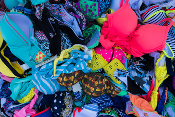Colorful bikini swimsuits in a basket at summer street market.