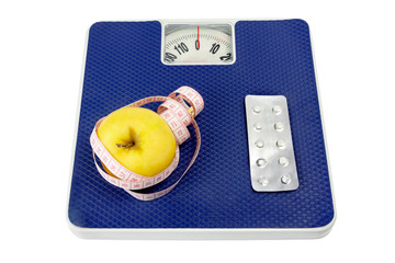 Healthy lifestyle concept. On the scales lie: on the one hand an apple and a measuring tape, on the other hand a medicine.