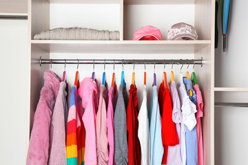 Wardrobe with stylish girl's clothes hanging on rack