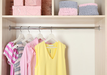 Stylish girl's clothes hanging in wardrobe, closeup