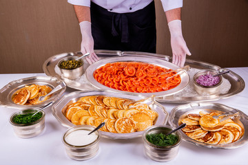 The humpback salmon on a dish, is served with pancakes, greens and sour cream