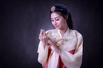 Beautiful Korean girl in Hanbok culture dress. Fair skin and adorable. With black background.