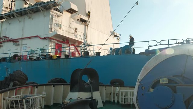 Towing ships at sea. The sea tow comes close to the cargo vessel for towing. A man in a helmet on the deck of the ship.