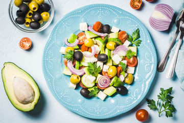 Avocado olives greek salad on blue plate. Top view, space for text.