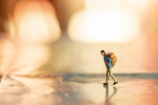 Travel Concept. Two traveler miniature figures with backpack walking on world map under sunlight. - Powered by Adobe