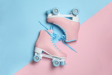 Pair of stylish quad roller skates on color background, top view