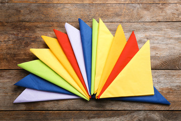 Colorful paper napkins on wooden background, top view