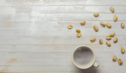 Fototapeta na wymiar Pistachio bean with coffee mug on white wooden floor with empty