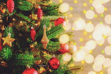 Decorated Christmas tree on soft yellow lights with bokeh effect background. Festive composition with fir and blurry sparkling backdrop, new year holiday decorations. Close up, copy space.