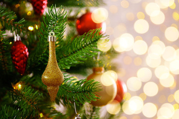 Decorated Christmas tree on soft yellow lights with bokeh effect background. Festive composition with fir and blurry sparkling backdrop, new year holiday decorations. Close up, copy space.