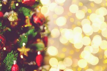 Decorated Christmas tree on soft yellow lights with bokeh effect background. Festive composition with fir and blurry sparkling backdrop, new year holiday decorations. Close up, copy space.