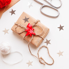 DIY presents wrapped in craft paper. Gifts tied with white and red threads with red Christmas tree symbol. Christmas and New Year holiday background.