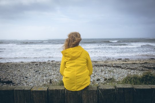 Woman Sitting On The Fence In The Beach