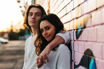 Portrait of young couple leaning on brick wall