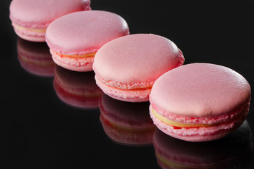 French macarons. Stack pink rose macaron  isolated on dark,  black mirror background. Colorful macaroons