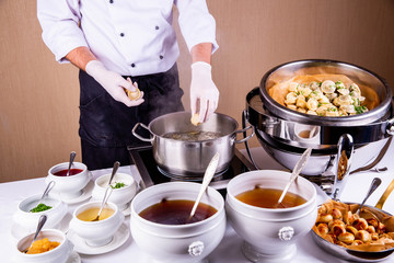 The cook throws pelmeni in the boiling water with spices