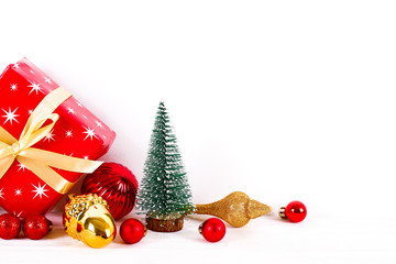 Minimalistic festive composition with small christmas tree, wrapped present and colorful matte balls. Fancy beautiful decoration for christmas pine tree. Background, copy space, close up, front view.