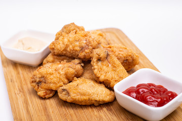 Fried breaded chicken wings on a wooden board.
