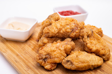 Fried breaded chicken wings on a wooden board.
