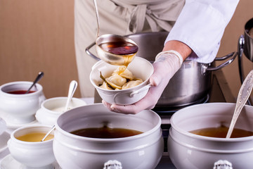 Giving of pelmeni with meat, filled in with meat broth with bay leaf