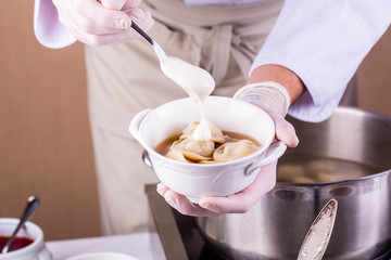 Meat broth with boiled pelmeni and sour cream
