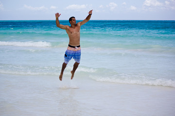 Junger Mann springt am Strand von Xpu Ha in Mexico auf der Halbinsel Yucatan bei Tulum