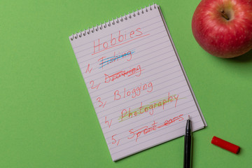 Hobbies list wrote on a spiral notebook. Above view with copy space